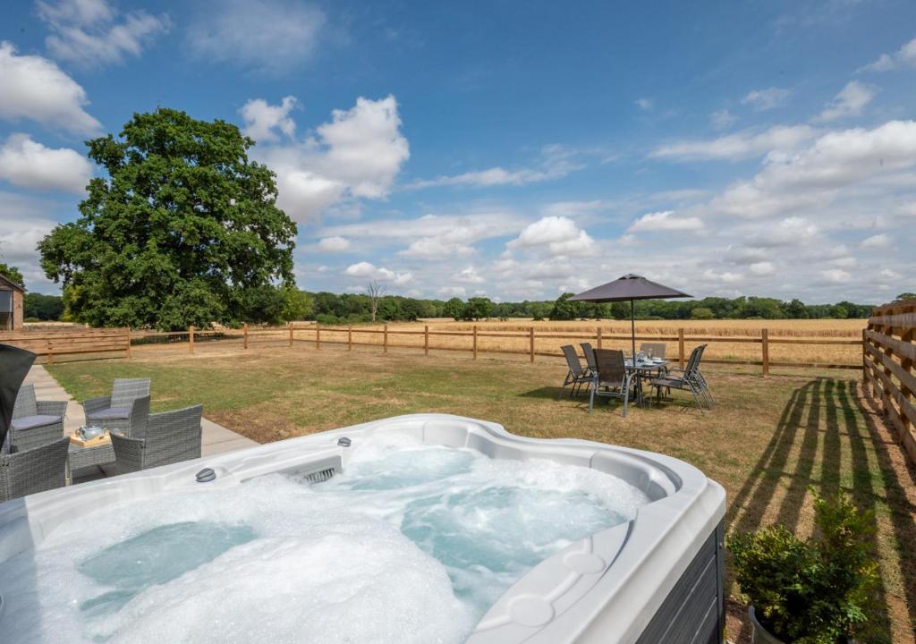 a hot tub in a yard with a table and chairs at The Cartlodge in Woolpit