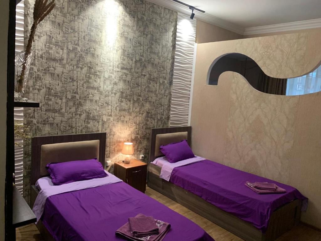 Dos camas en una habitación con sábanas moradas. en Downtown-home in the heart of old Tbilisi, en Tiflis