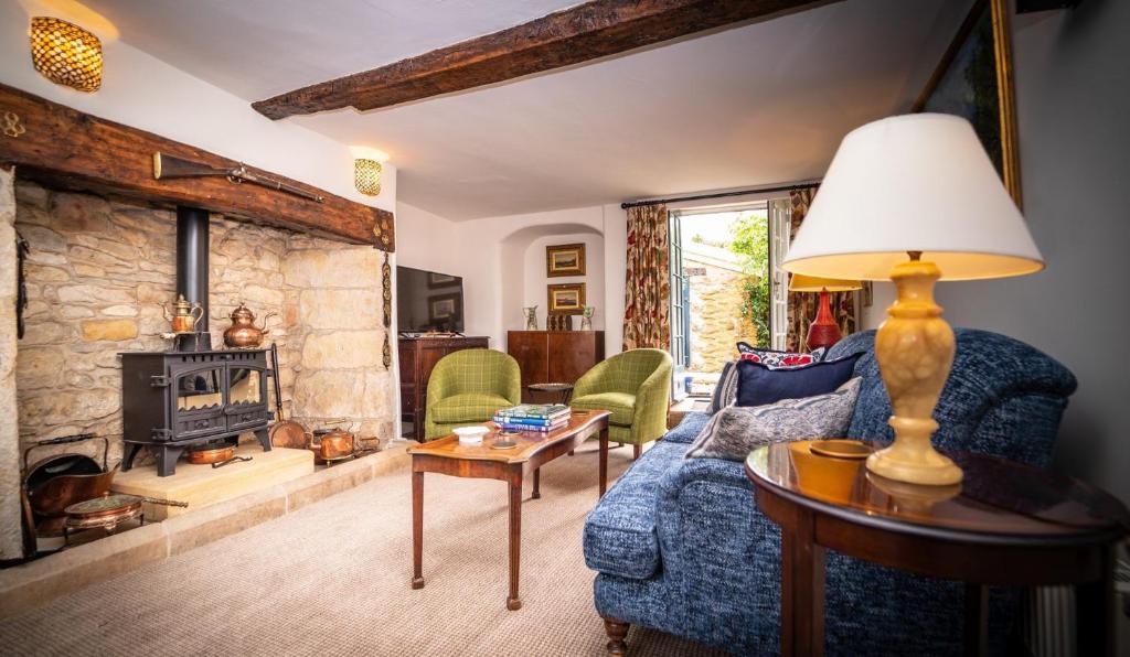 a living room with a blue couch and a stone fireplace at The Sherborne Cottage in Sherborne