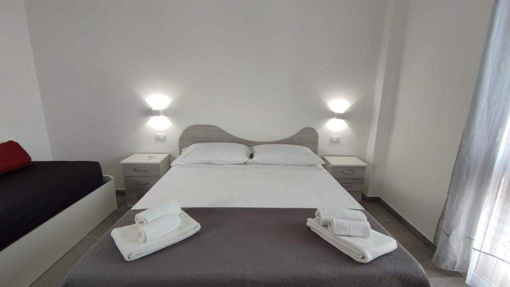 a bedroom with a large white bed and two white shoes at Case Vacanze Blue Sea in Mascali