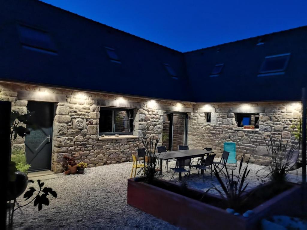 ein Steinhaus mit einer Terrasse mit einem Tisch und Stühlen in der Unterkunft Belle maison en pierre in Cléder
