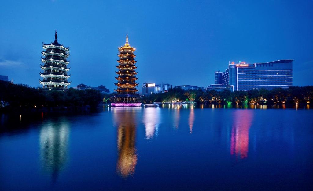 two towers on a lake in a city at night at Lijiang Waterfall Hotel Guilin in Guilin