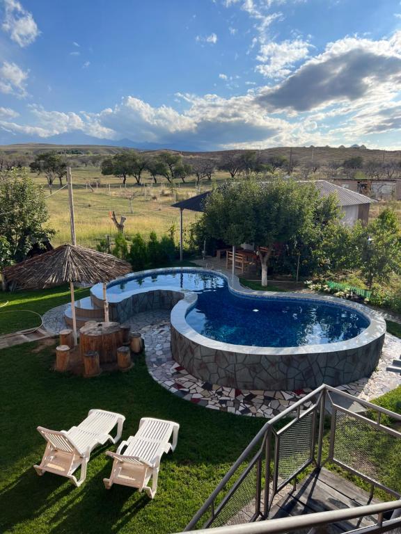 einen Pool in einem Garten mit zwei Stühlen in der Unterkunft Guest house and yurt camp "Aktan" in Bokonbayevo