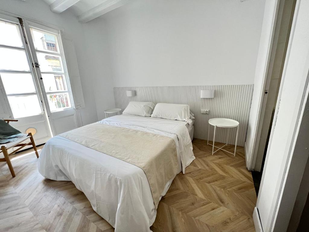 a white bedroom with a large bed and a table at The MO GOTIC in Barcelona