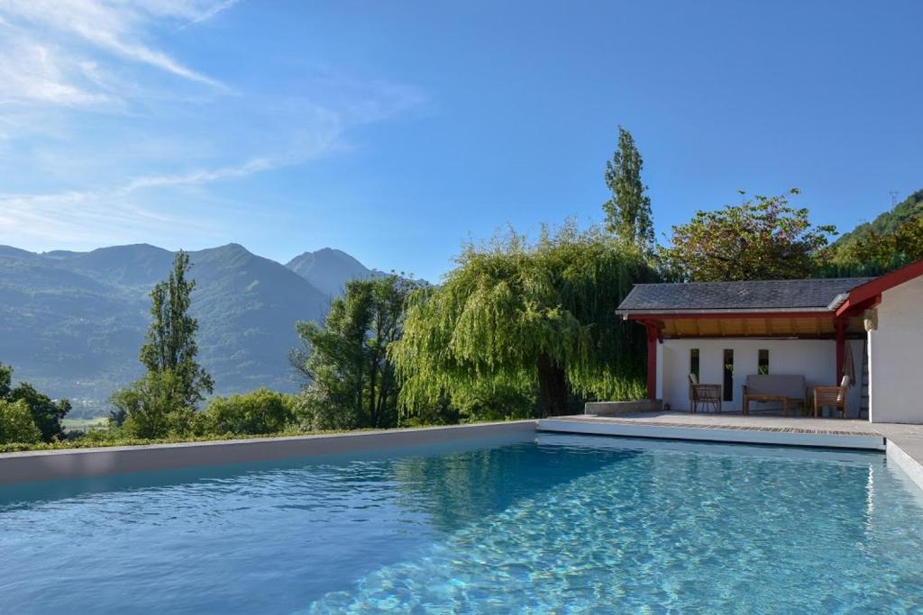 uma piscina com casa e montanhas ao fundo em Le Chalet des Pyrénées em Arcizans-Avant