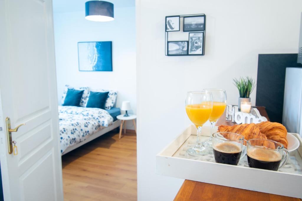 um quarto com uma bandeja de comida e copos de sumo de laranja em Le Rétro Chic - T2 Haut Standing au cœur de Corbeil - 48 m2 em Corbeil-Essonnes