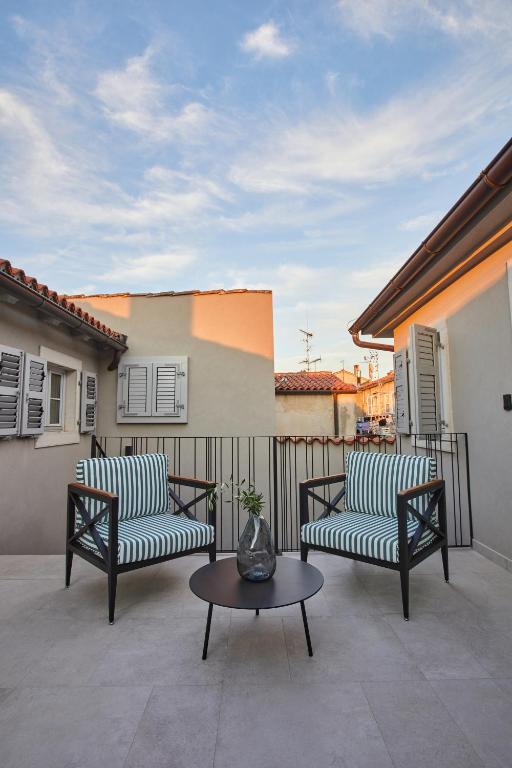 a patio with two chairs and a table and a fence at Martis Forum Heritage Hotel & Residence in Poreč