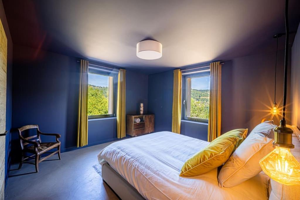 a blue bedroom with a bed and two windows at Le 11 des Bouchaux, Gîte d&#39;exception in La Bresse