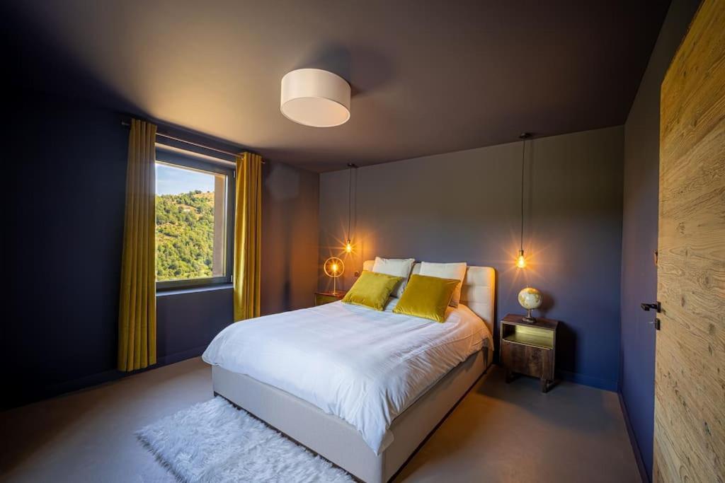 a bedroom with a bed with yellow pillows and a window at Le 11 des Bouchaux, Gîte d&#39;exception in La Bresse
