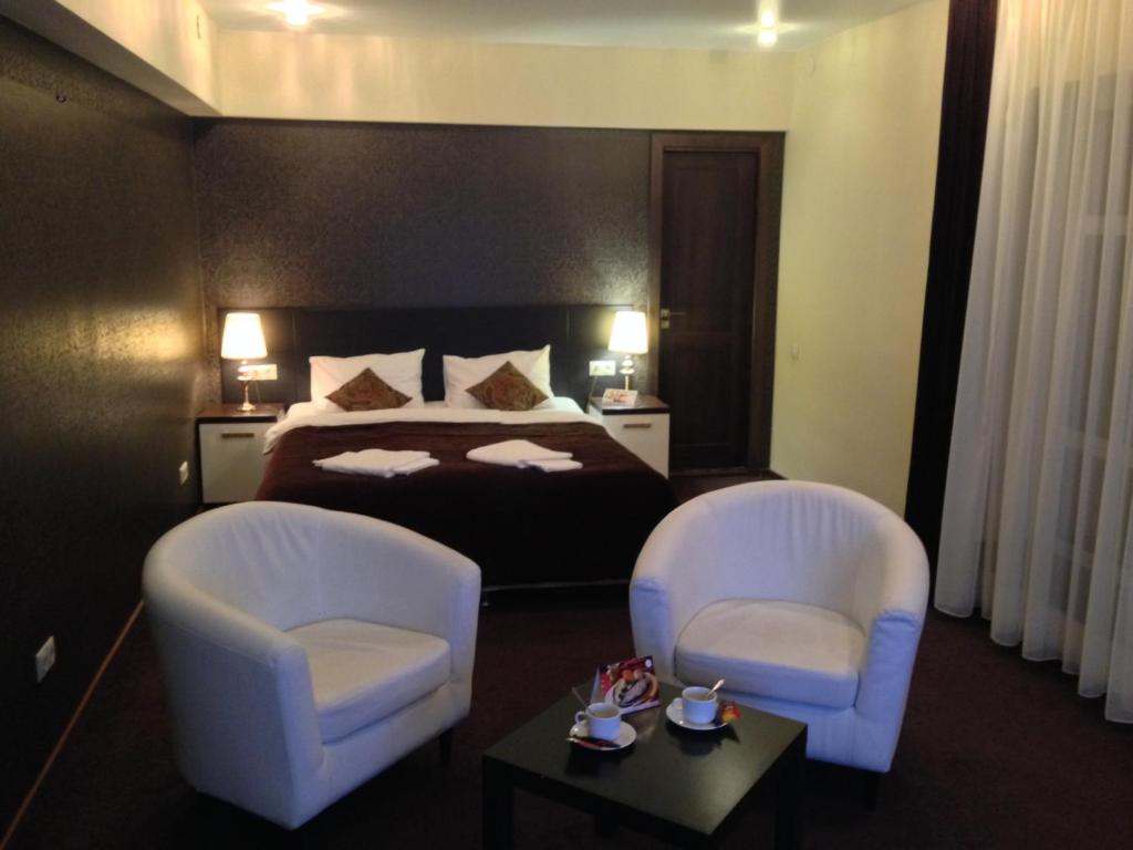 a bedroom with a bed and two chairs and a table at History Hotel in Vologda