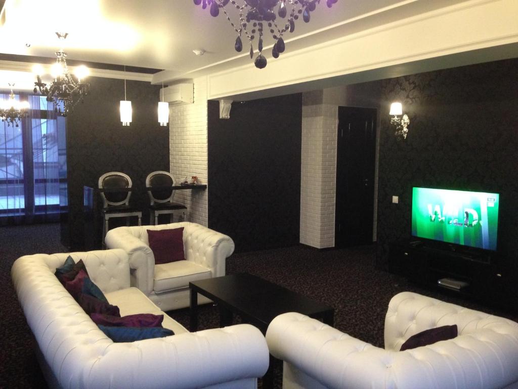 a living room with white furniture and a flat screen tv at History Hotel in Vologda