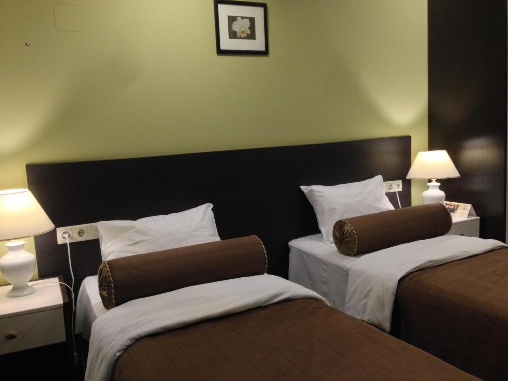 a hotel room with two beds and two lamps at History Hotel in Vologda