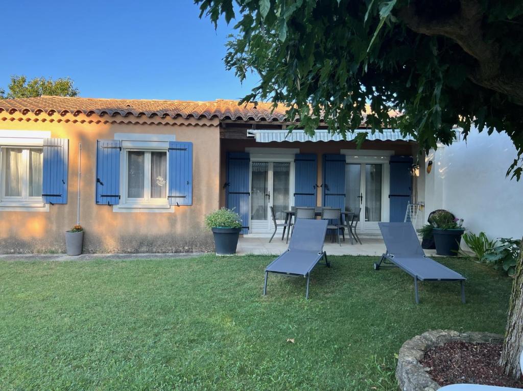 a house with blue doors and chairs in the yard at La Villa de l'Aygues in Camaret-sur-Aigues