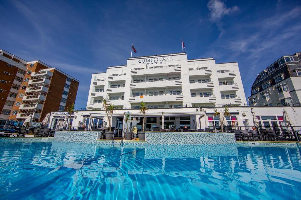 a hotel with a large swimming pool in front of a building at Cumberland Hotel - OCEANA COLLECTION in Bournemouth