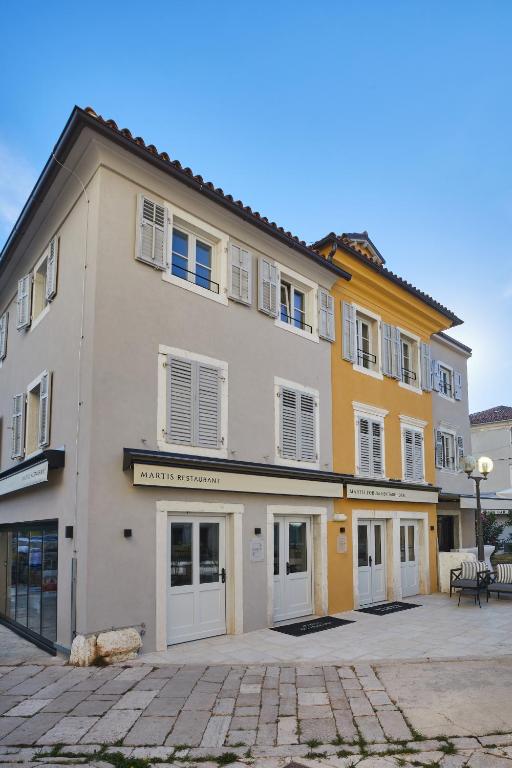 a large yellow building with white doors and windows at Martis Forum Heritage Hotel & Residence in Poreč