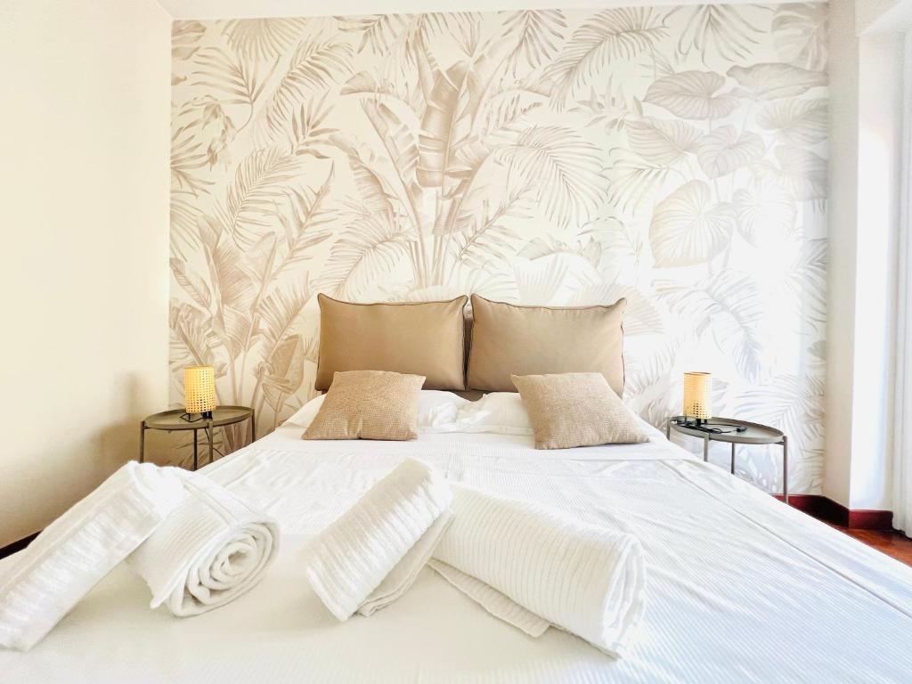ein Schlafzimmer mit einem weißen Bett und einer tropischen Tapete in der Unterkunft Suite Astraldi - a 2 minuti dall'Ariston in Sanremo