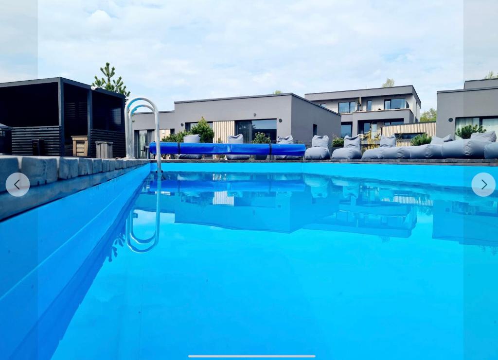 a swimming pool with blue water in front of buildings at Vieno kambario butas-studija in Palanga