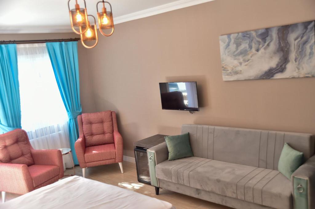 a living room with a couch and two chairs and a tv at Noya Köşk Otel in Adalar