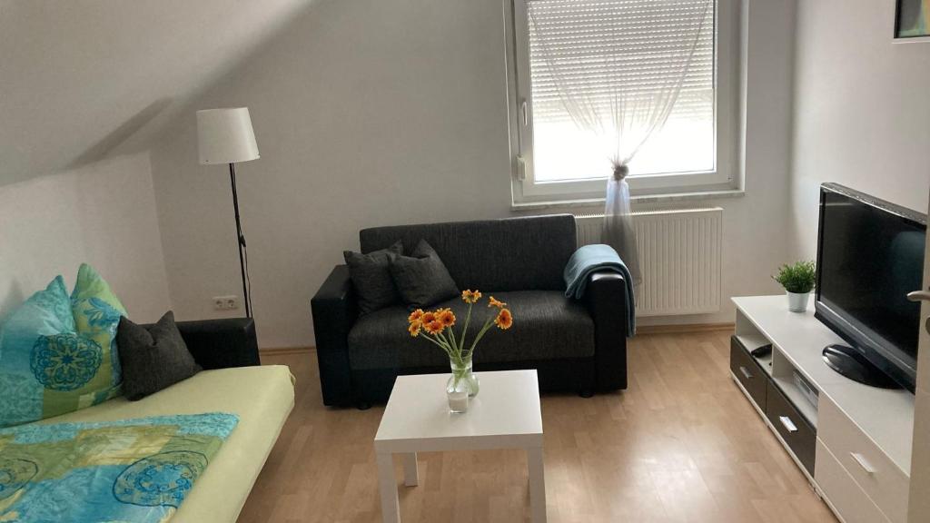 un soggiorno con un divano e un tavolo con fiori di Ferienwohnung Lipp a Waldstetten
