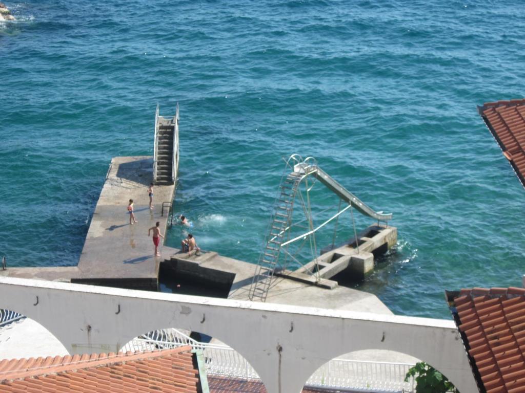 a dock in the ocean with people in the water at Apartment Doris in Rijeka