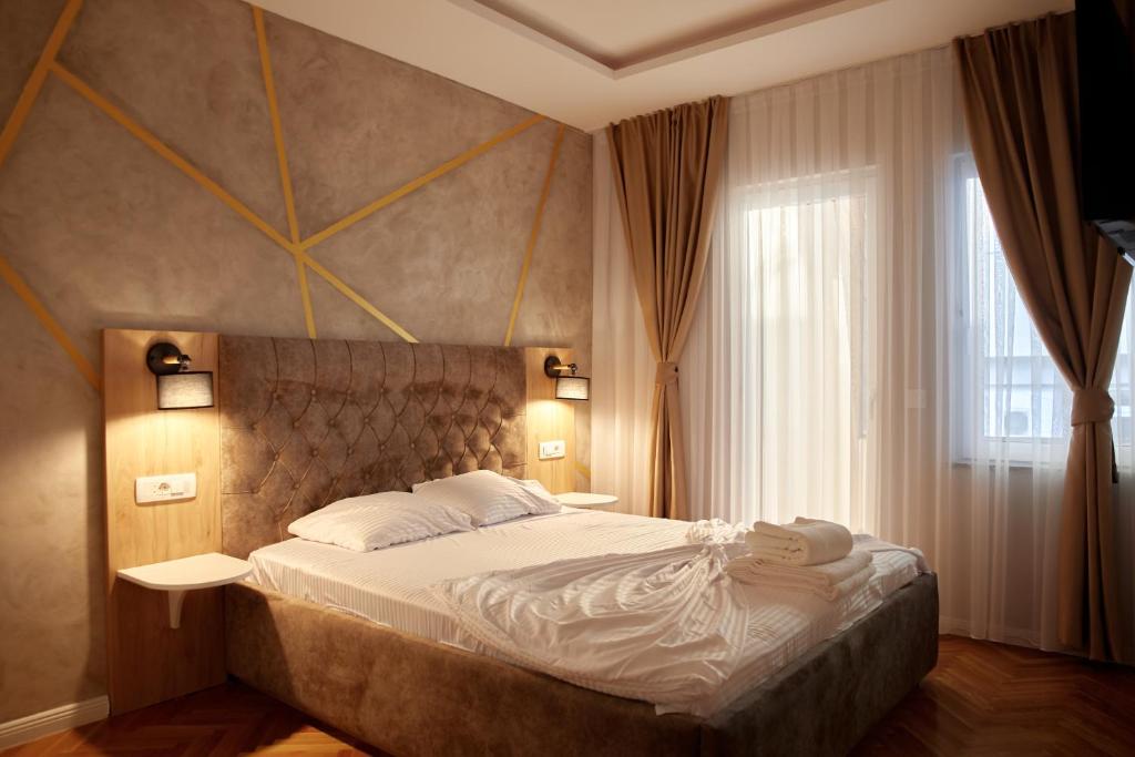 sypialnia z dużym łóżkiem i oknem w obiekcie Amico Hotel w Prisztinie