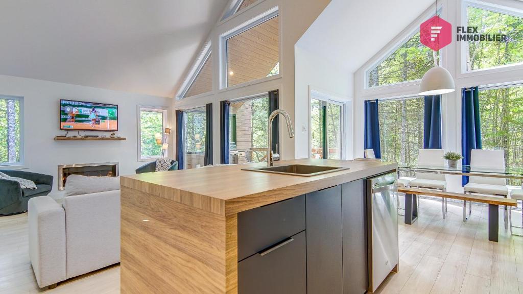 a kitchen with a sink and a bunch of windows at Le Bleu Bourgeois de Portneuf - Natural Elegance - Hot tub, sauna and pool in Pont-Rouge