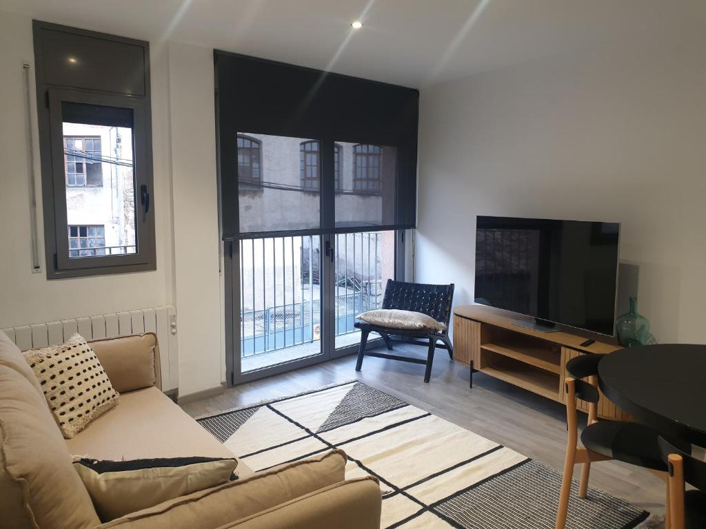 uma sala de estar com um sofá e uma televisão em Apartament Cèntric a Ribes de Freser Vall de Núria em Ribes de Freser