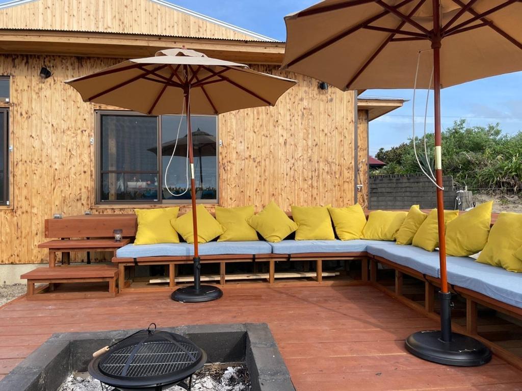 eine Bank mit Kissen und einem Regenschirm auf einer Terrasse in der Unterkunft Amami - Hotel - Vacation STAY 09731v in Amami