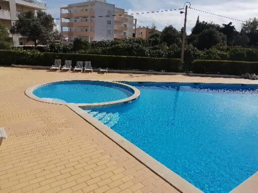 una gran piscina azul con sillas y un edificio en T1 em Alvor, en Alvor