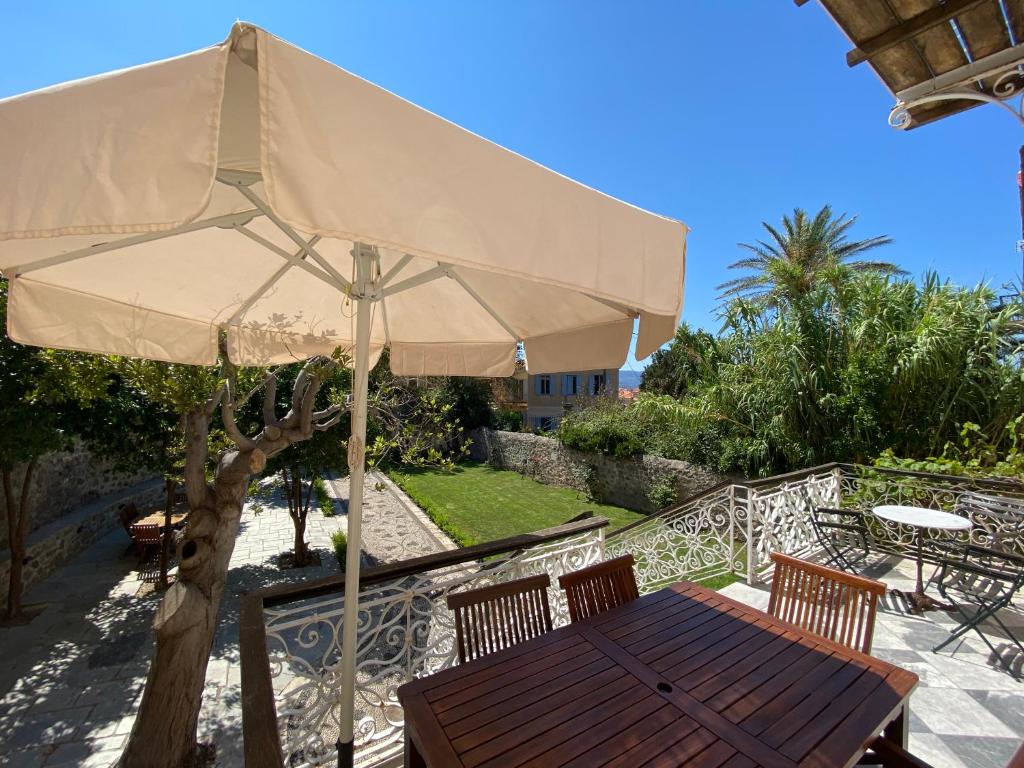 a wooden table with a large umbrella on a balcony at Eleana Residence in Mythimna