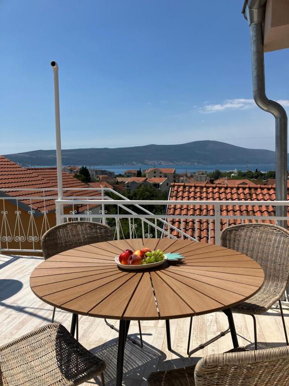 una mesa de madera con un bol de fruta en el balcón en Mia Casa, en Tivat