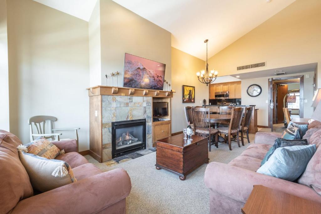 a living room with a fireplace and a dining room at Ski In Ski Out Conde Nast and Forbes Award Winner Two Bedroom Pool Hot Tub Gym 415 in Park City