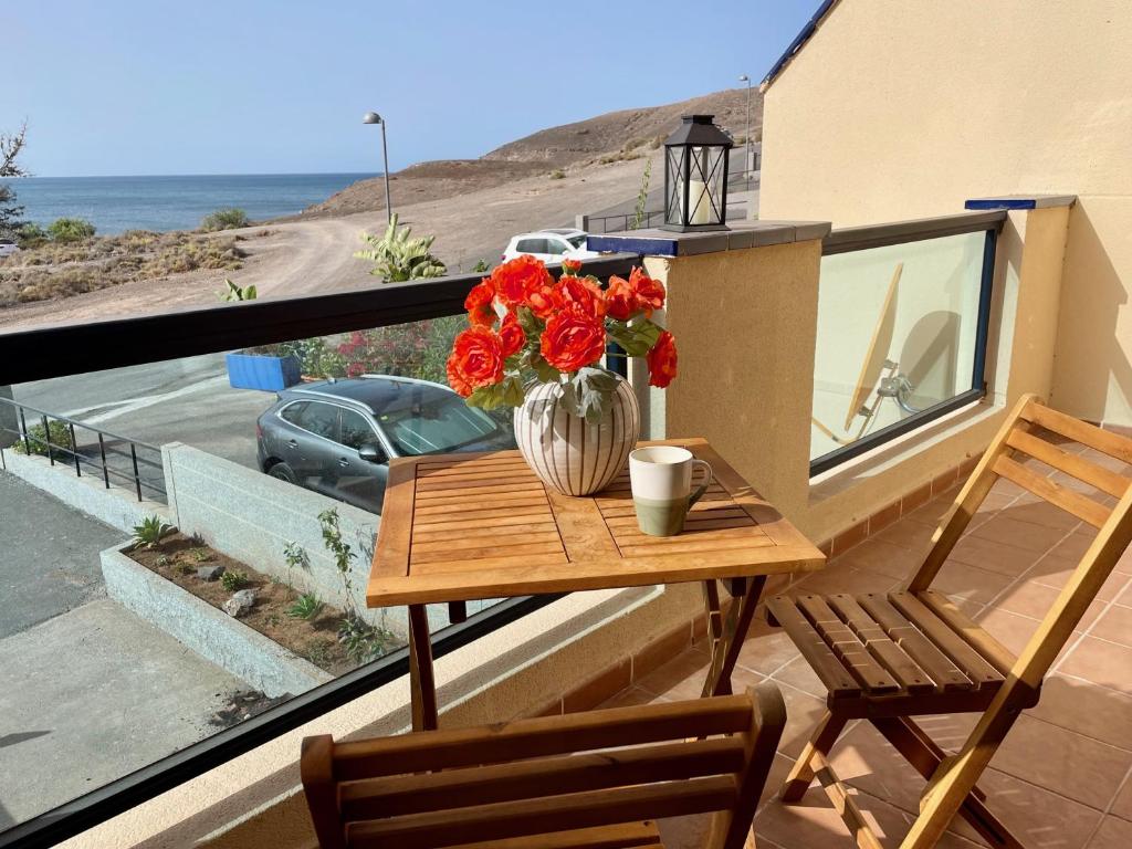 ein Tisch mit einer Vase mit Blumen auf einem Balkon in der Unterkunft Casa La Ola - Idylle am Meer, La Lajita in Lajita