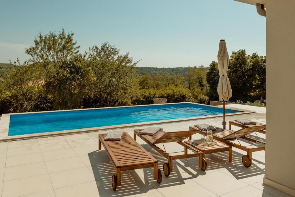 a pool with chairs and a table and an umbrella at Casa Cavi Istria in Oprtalj