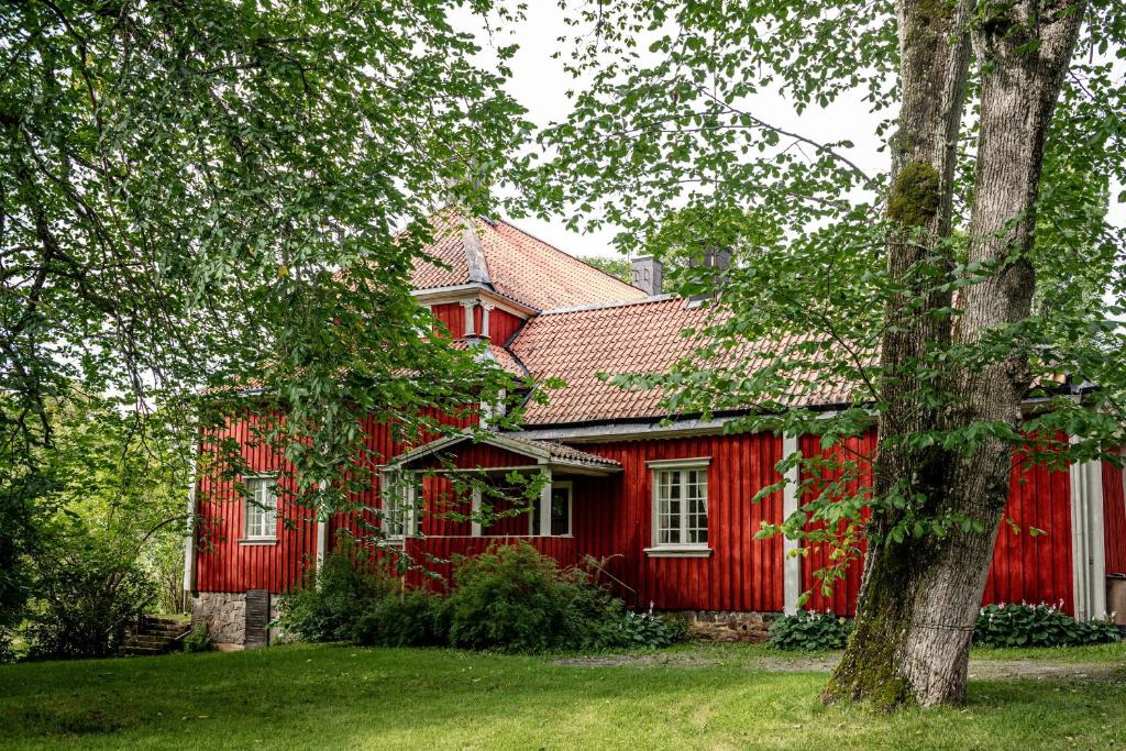 een rood huis met een boom ervoor bij Borgviks herrgårdsflygel in Borgvik