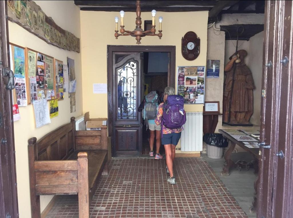 Albergue San Javier - Solo para peregrinos في أستورغا: شخصان يسيران في ممر إلى مبنى