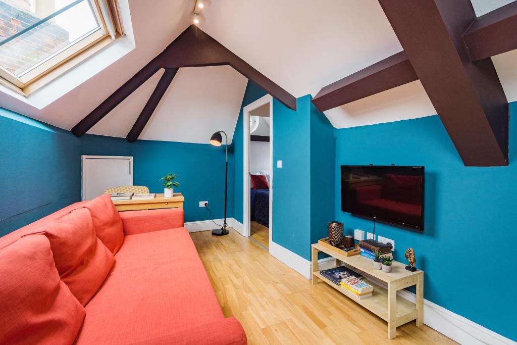 ein Wohnzimmer mit einem roten Sofa und blauen Wänden in der Unterkunft Sunny Loft in Center of London in London