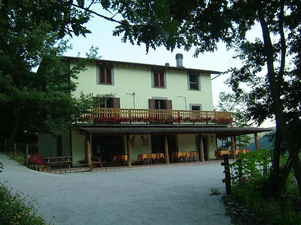 a large white house with a balcony and tables and chairs at Agriturismo Grisciano in Accumoli