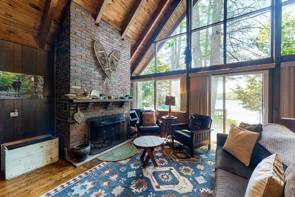 a living room with a brick fireplace and a couch at Cabin on Long Pond in Cornish