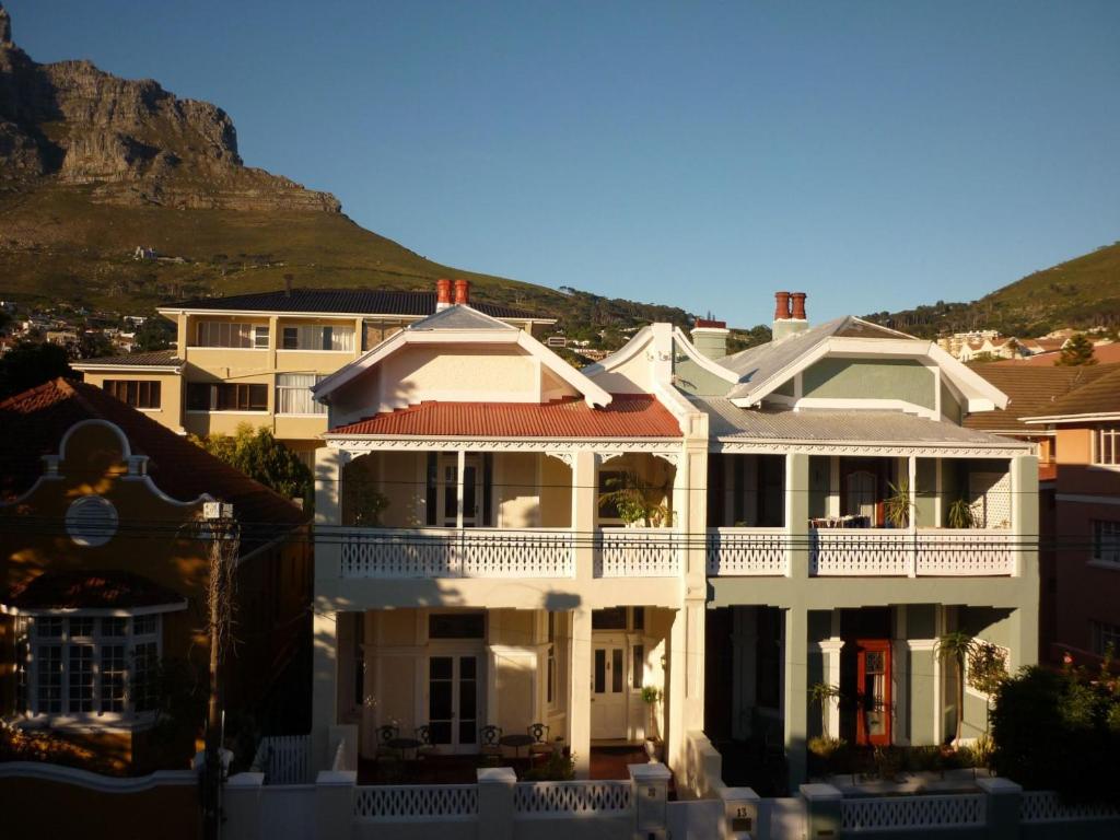 a white house with a balcony with a mountain in the background at The Cape Colonial Guest House in Cape Town