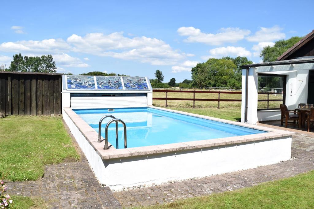 una piscina en un patio con una casa en Landhaus Hideaway mit Aussenpool, Sauna und Kamin, en Bosau