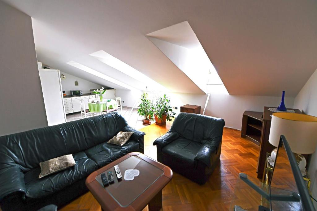 uma sala de estar com um sofá de couro preto e uma mesa em Apartment Fiumara em Rijeka