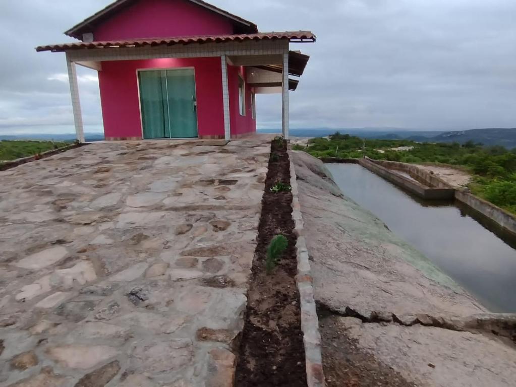 a pink house with a green door on top of a river at Chalé Pedro & Carmelita in Serra de São Bento