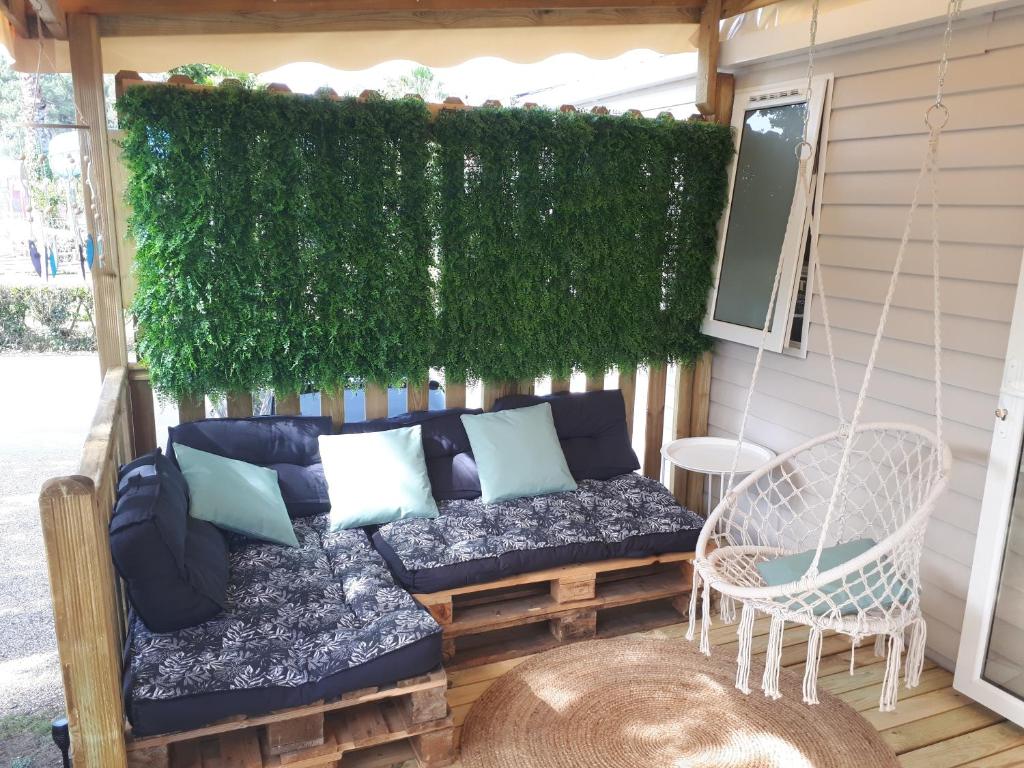 a porch with a couch and a green wall at En bord d'eau - charmant Mobil-home climatisé - Cap ferret in Lège-Cap-Ferret