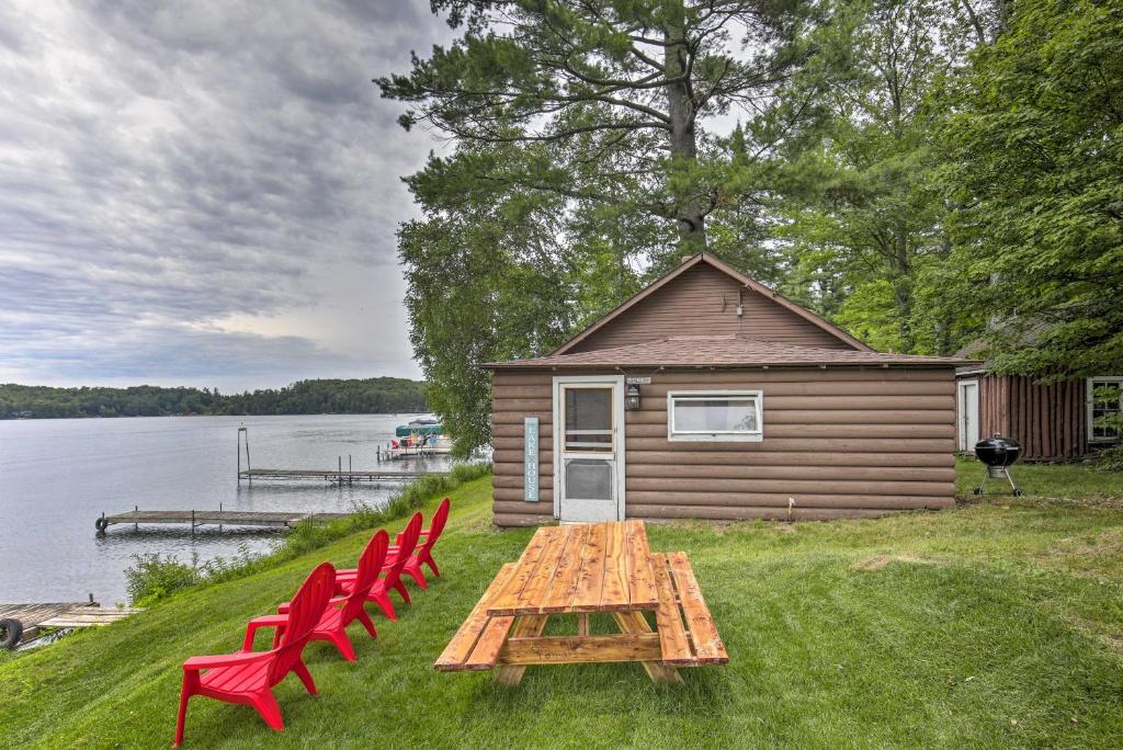 einem Picknicktisch mit roten Stühlen vor einer Hütte in der Unterkunft Lakefront Minocqua Cabin with Dock and Fire Pit! in Minocqua