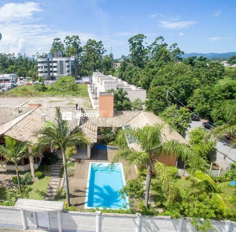 an aerial view of a house with a swimming pool and palm trees at Pousada ESQUINA DO ATLANTICO SUL in Tubarão