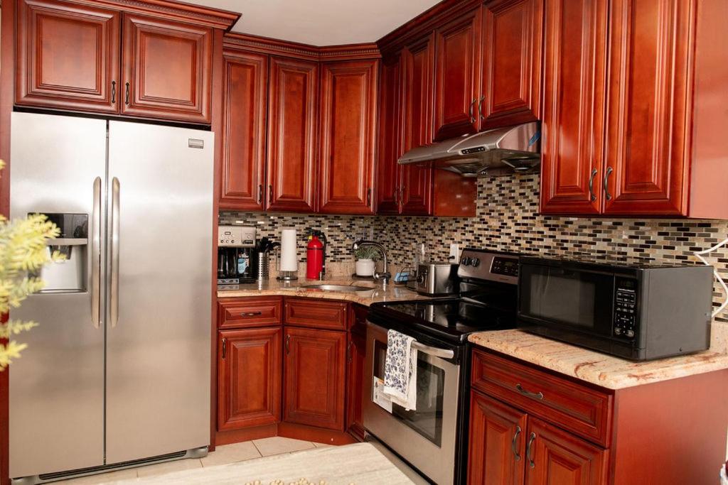 uma cozinha com armários de madeira e um frigorífico de aço inoxidável em Tonel Paradise 1BR private entrance Near JFK em Rosedale