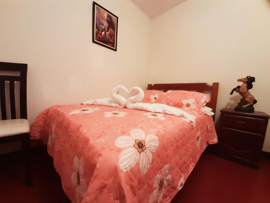 利馬的住宿－Maypa Lima Airport，一间卧室配有一张带粉红色床罩和鲜花的床。