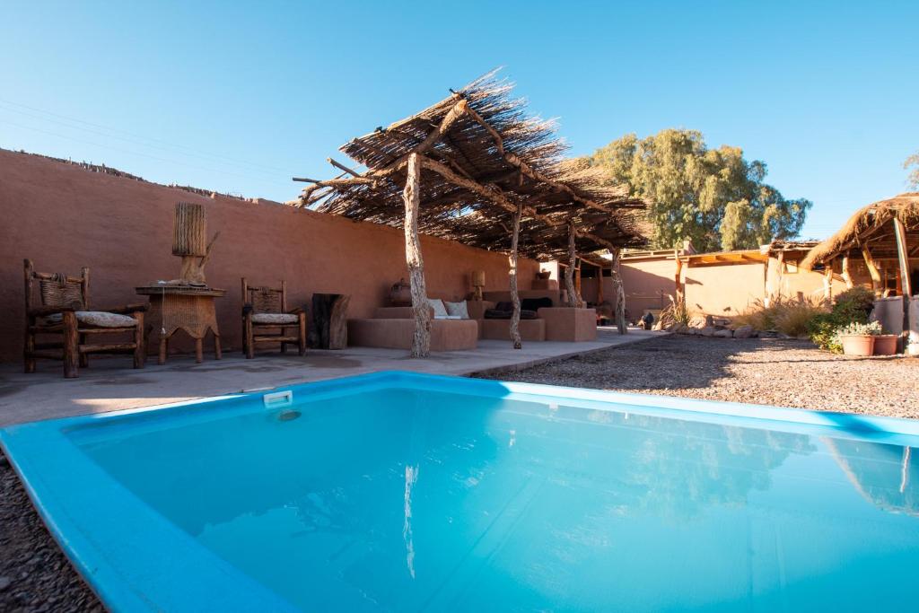 uma piscina azul em frente a uma casa em Hotel Pat'ta Hoiri em San Pedro de Atacama