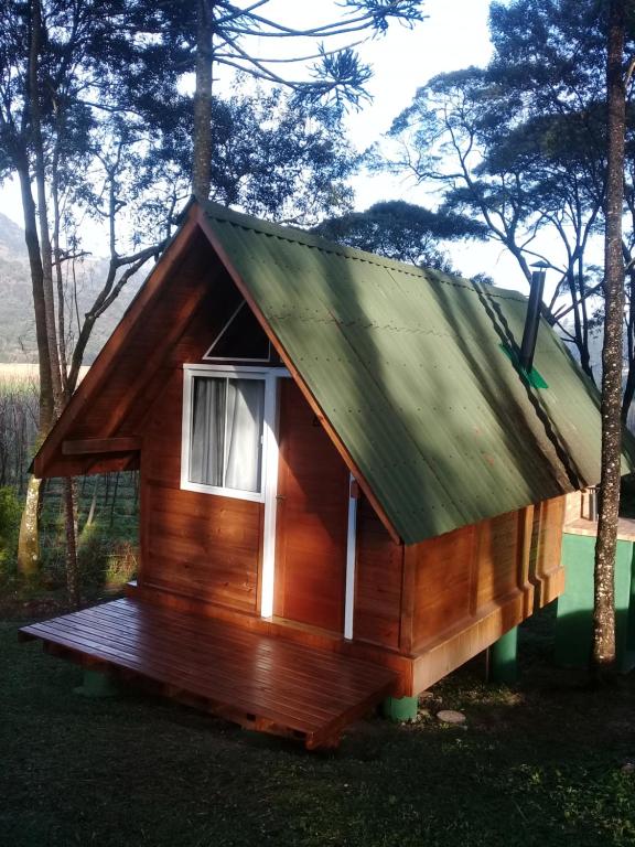 Cabaña de madera pequeña con techo verde en Chalés Snow, en Urubici